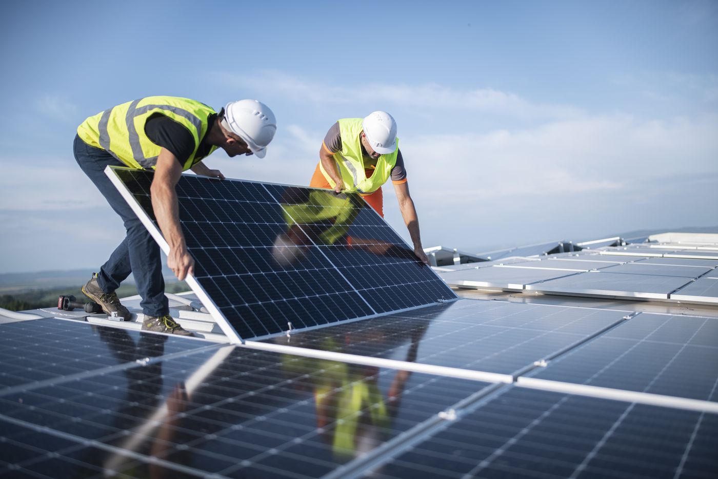 Installers carrying a solar panel into place on a rooftop